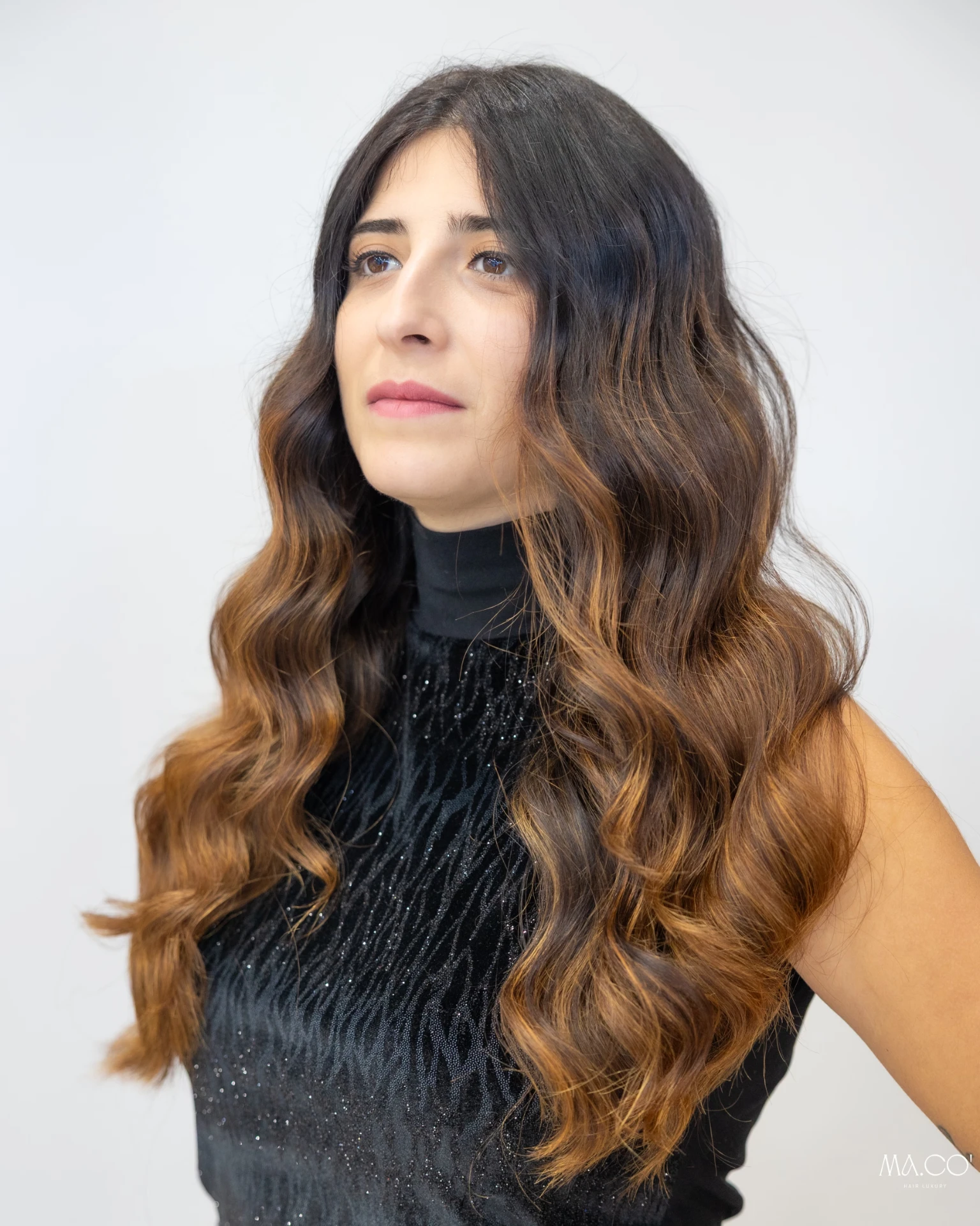 Cliente con lunghi capelli mossi e sfumature balayage dal castano al caramello